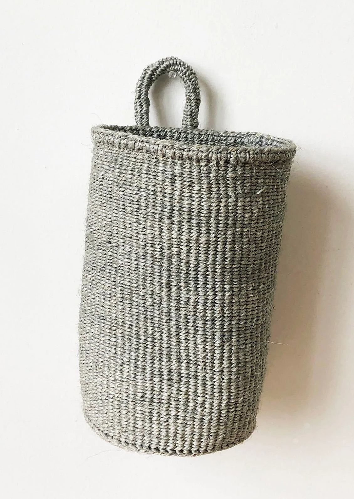 An oblong cylindrical basket woven from sisal in slate color.