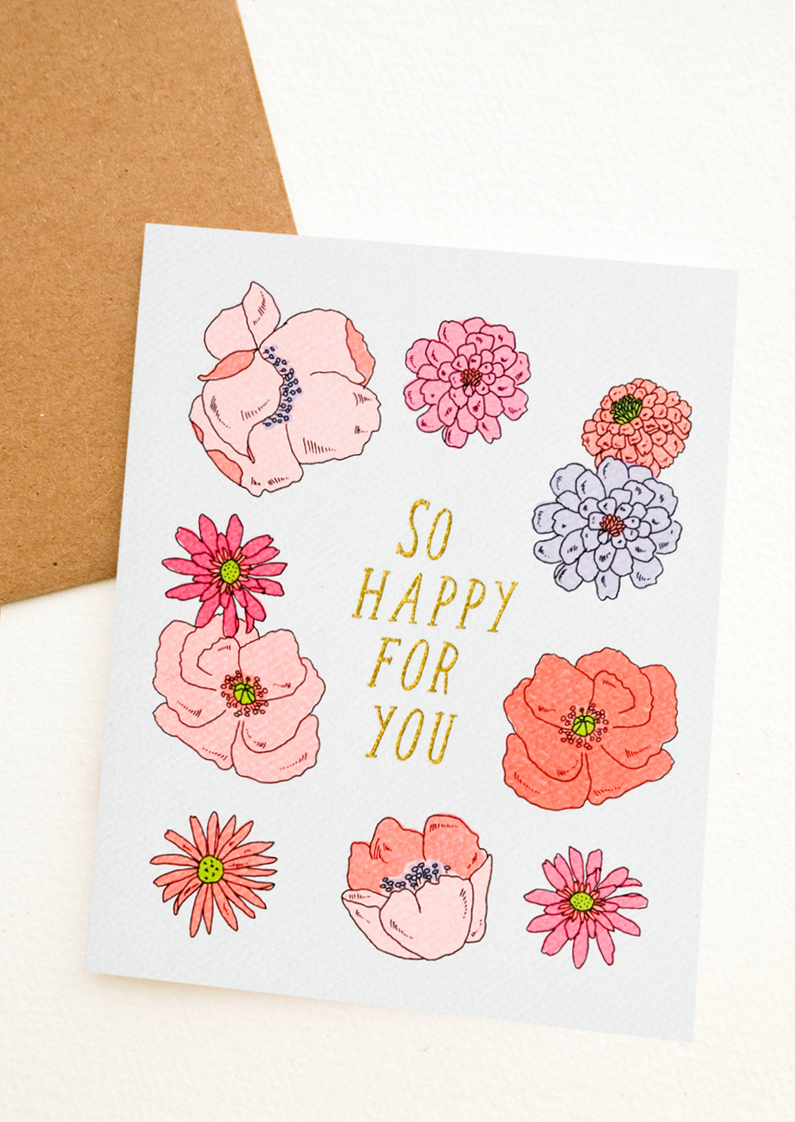 A floral print greeting card with gold text reading "So Happy For You".