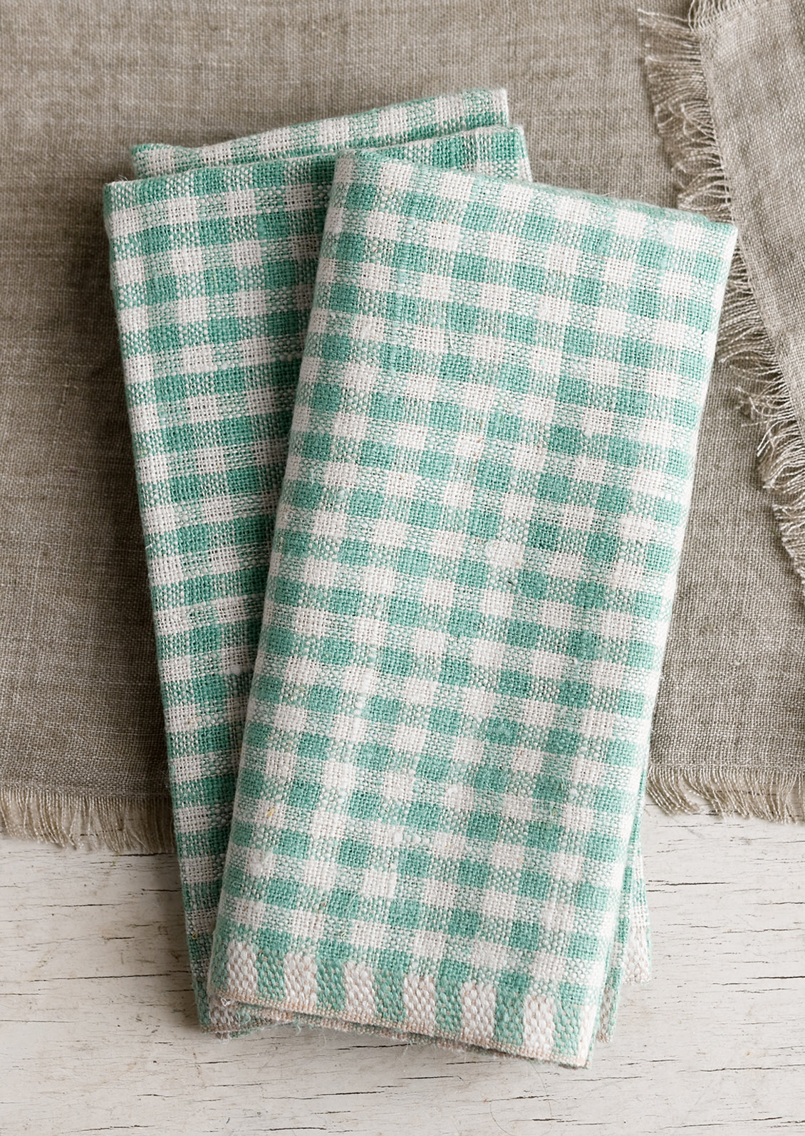 A pair of thick linen dinner napkins in spearmint gingham.