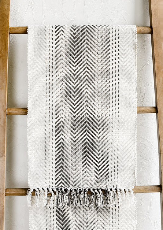 A cream textured cotton table runner with herringbone stitch down middle.