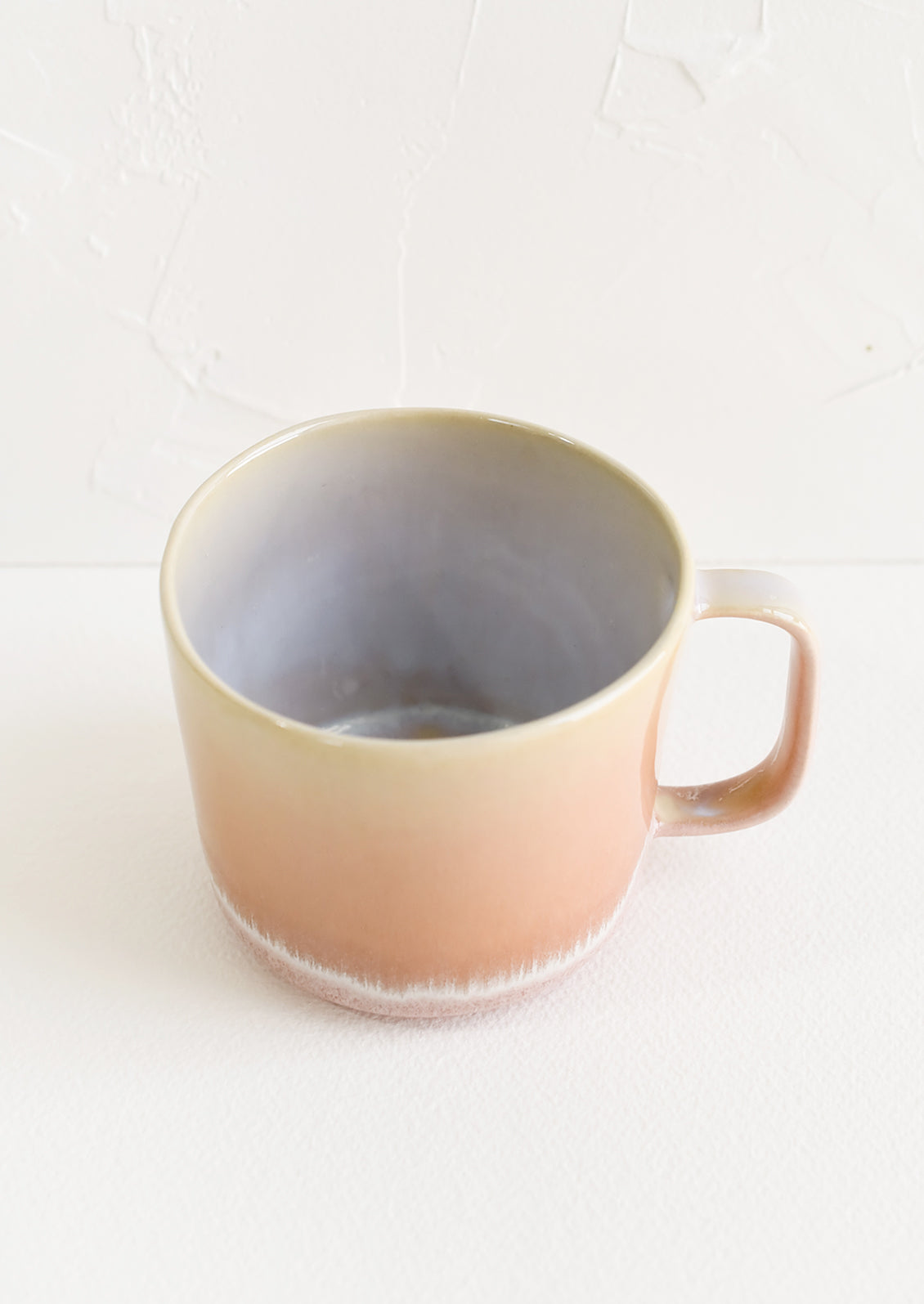 A ceramic mug in peach with ombre glaze.