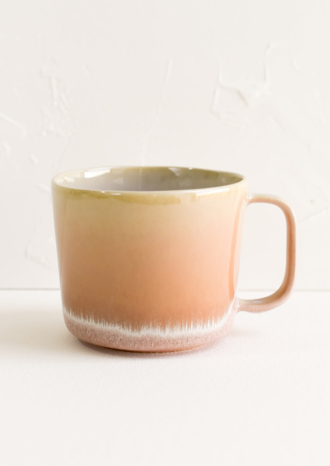 A ceramic mug in peach with ombre glaze.