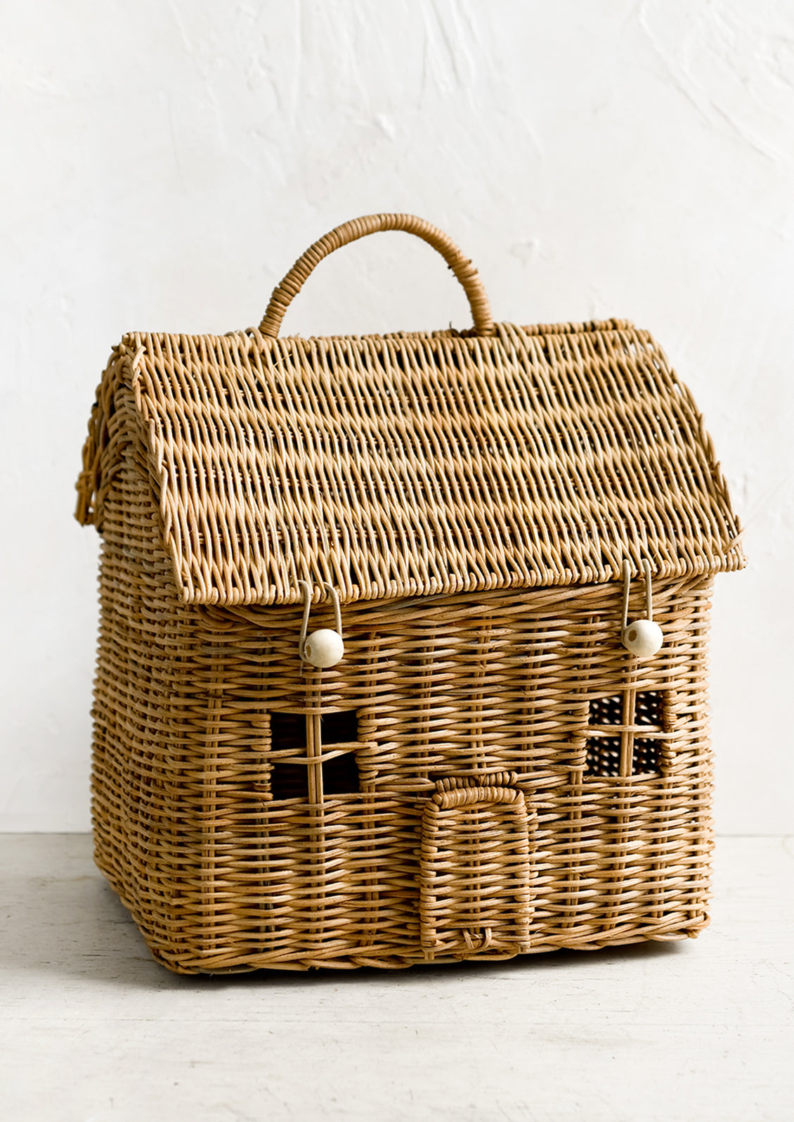 A rattan storage basket in the shape of a house.