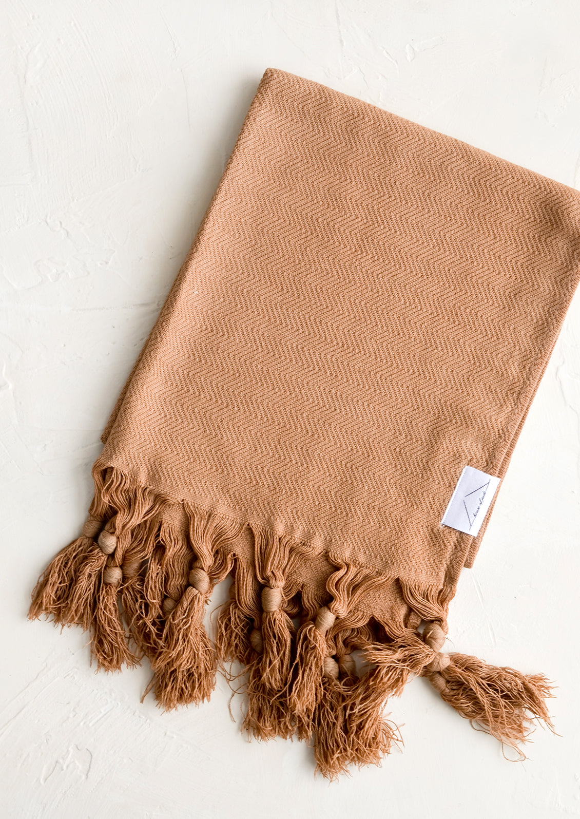 A turkish hand towel in chocolate brown with tonal fringed trim.