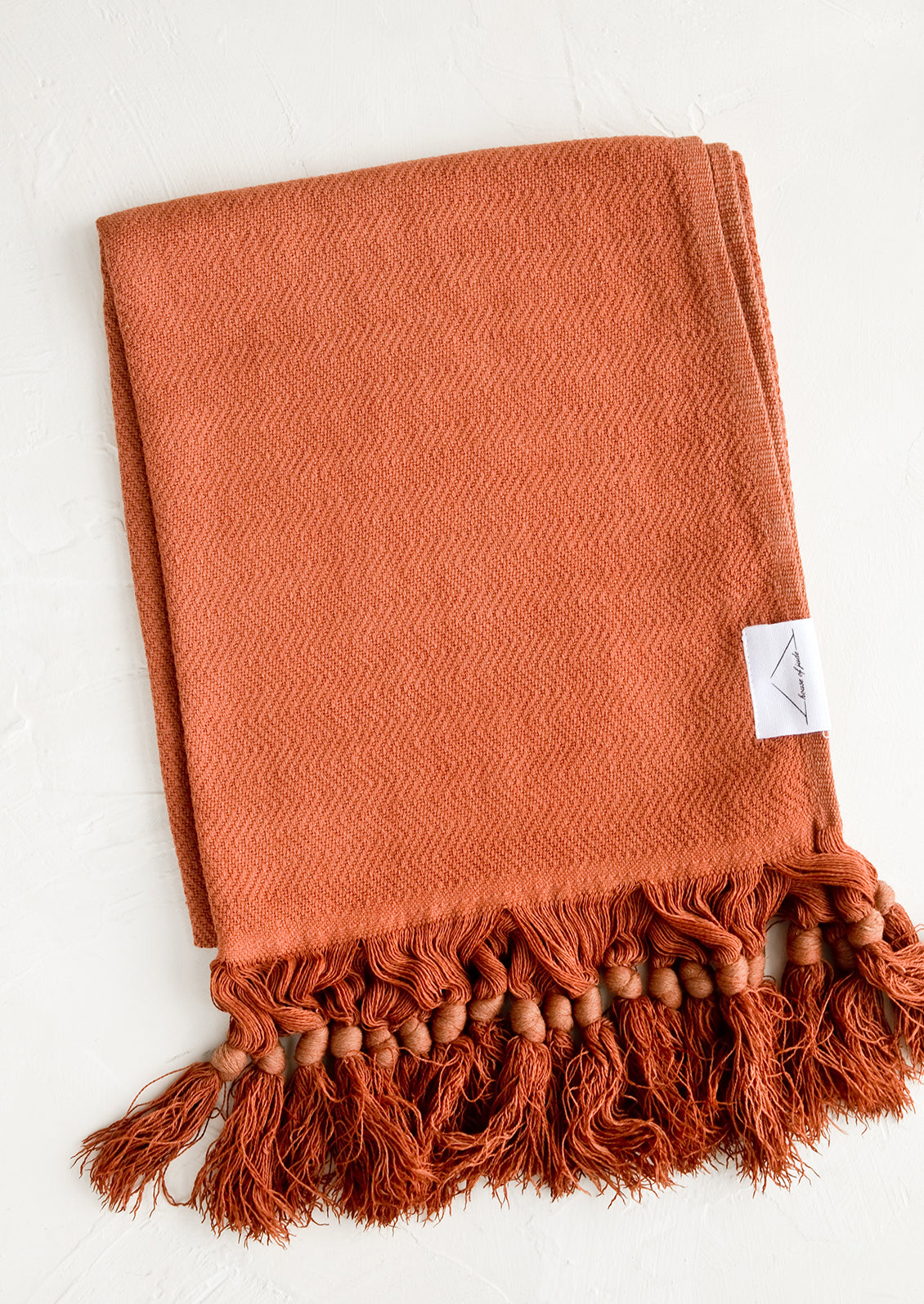 A turkish hand towel in cinnamon hue with tonal fringed trim.