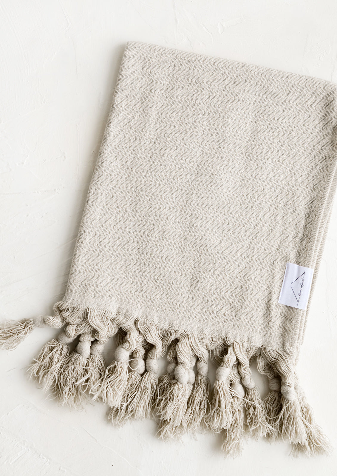 A turkish hand towel in warm oyster grey hue with tonal fringed trim.