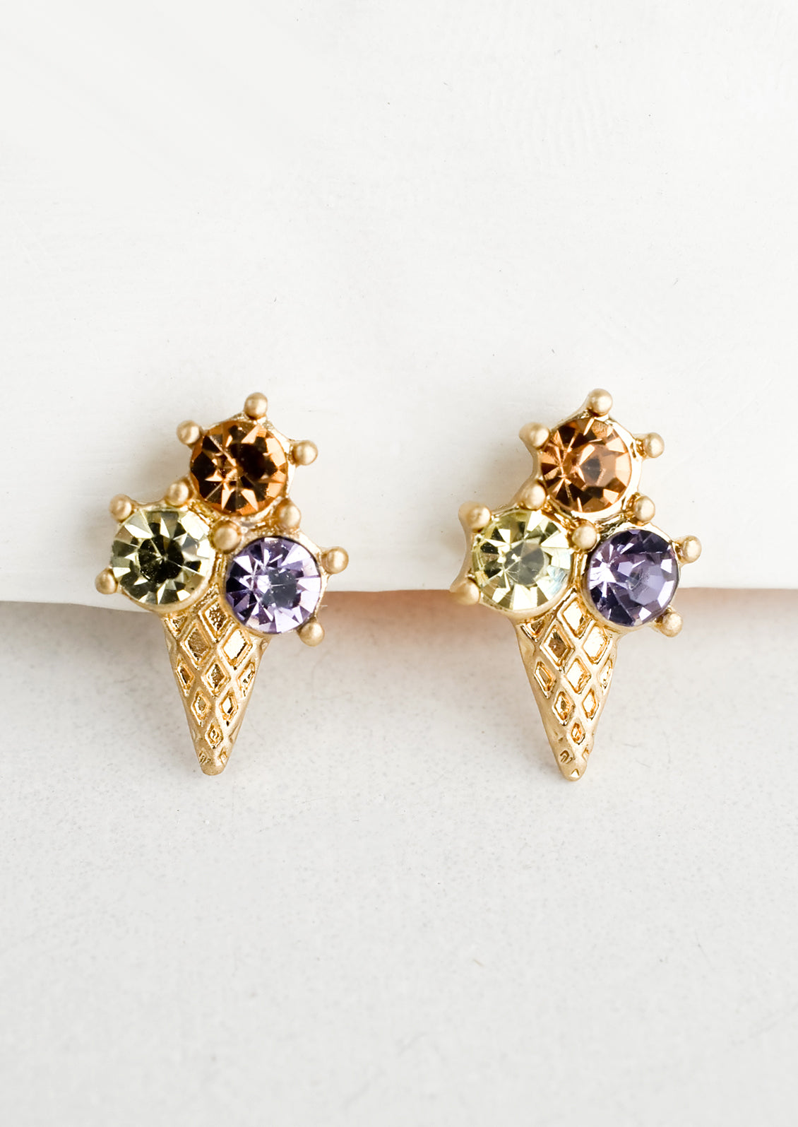 A pair of gold stud earrings in shape of ice cream cone with three different color "scoops".