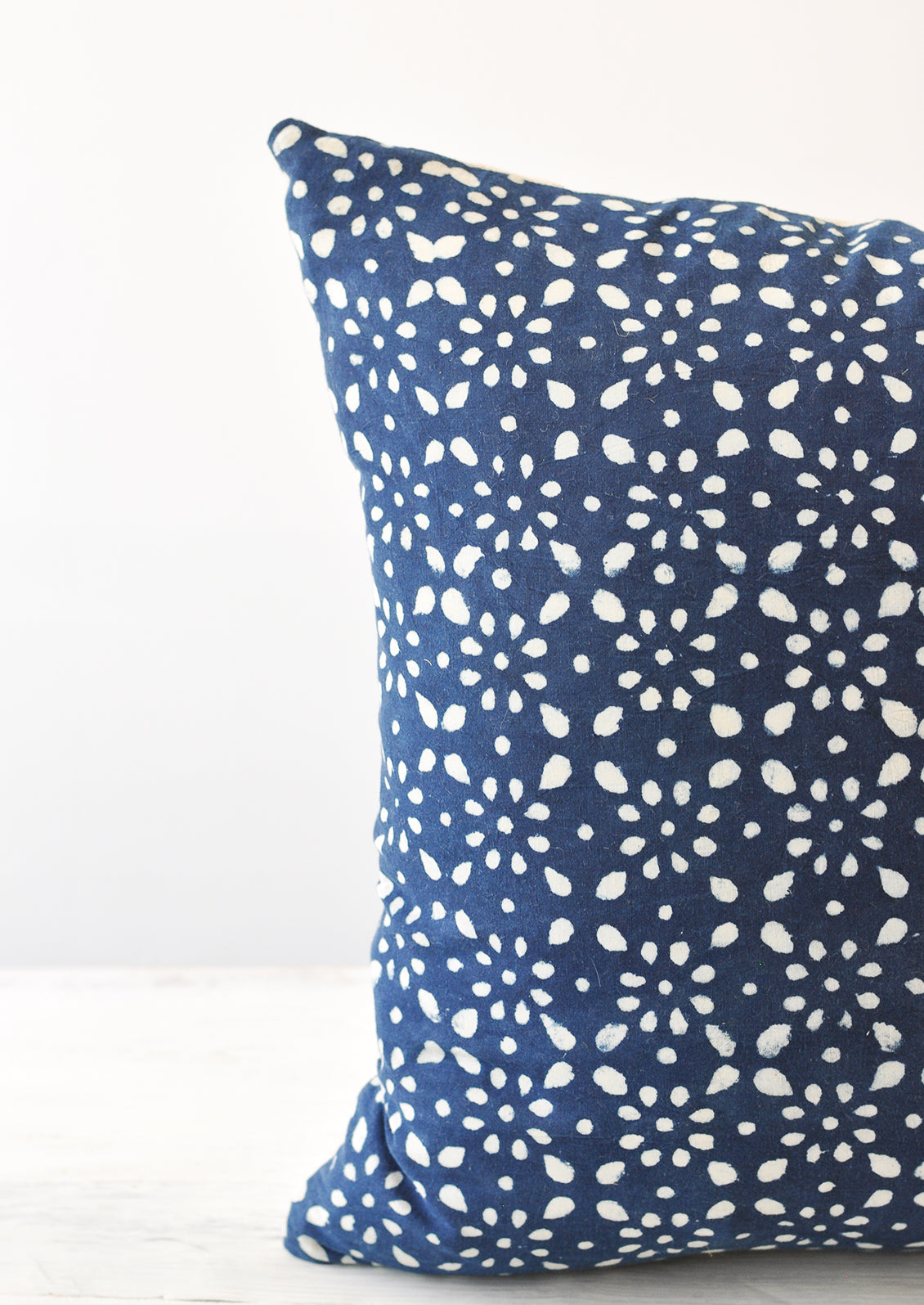 A detail shot of a square indigo and white block printed pillow.