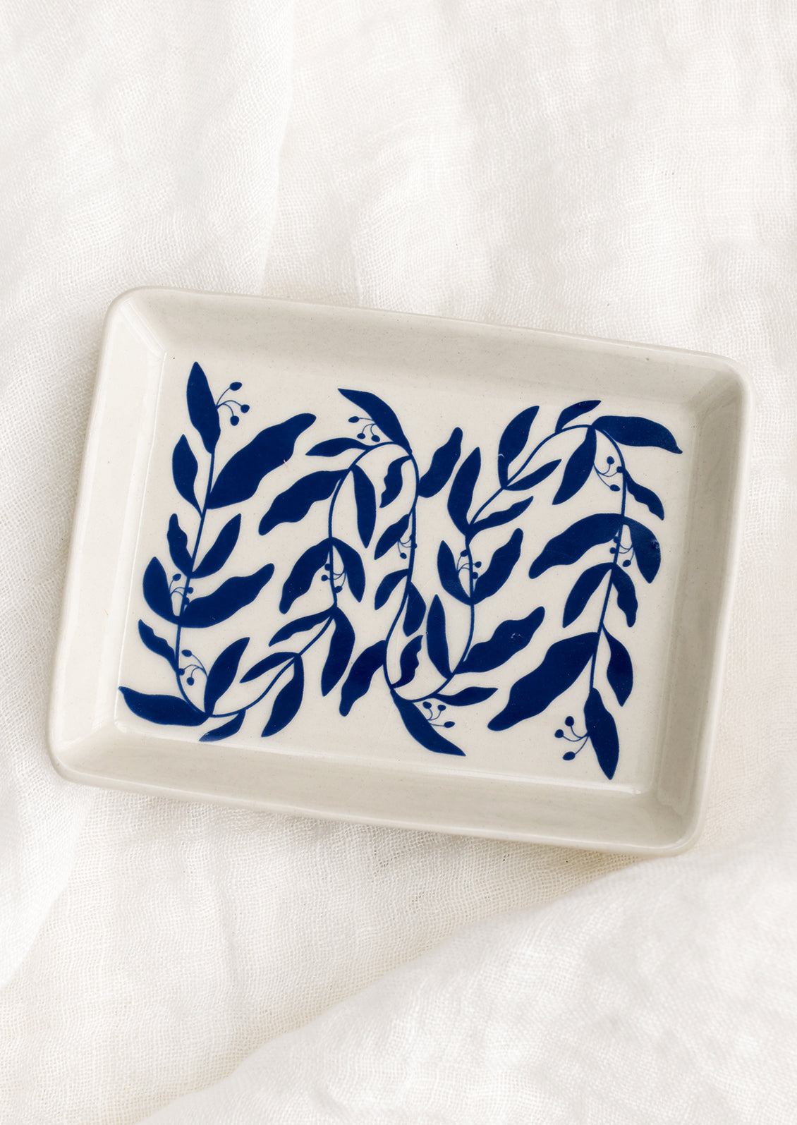 A rectangular white ceramic tray with allover blue leaf pattern.