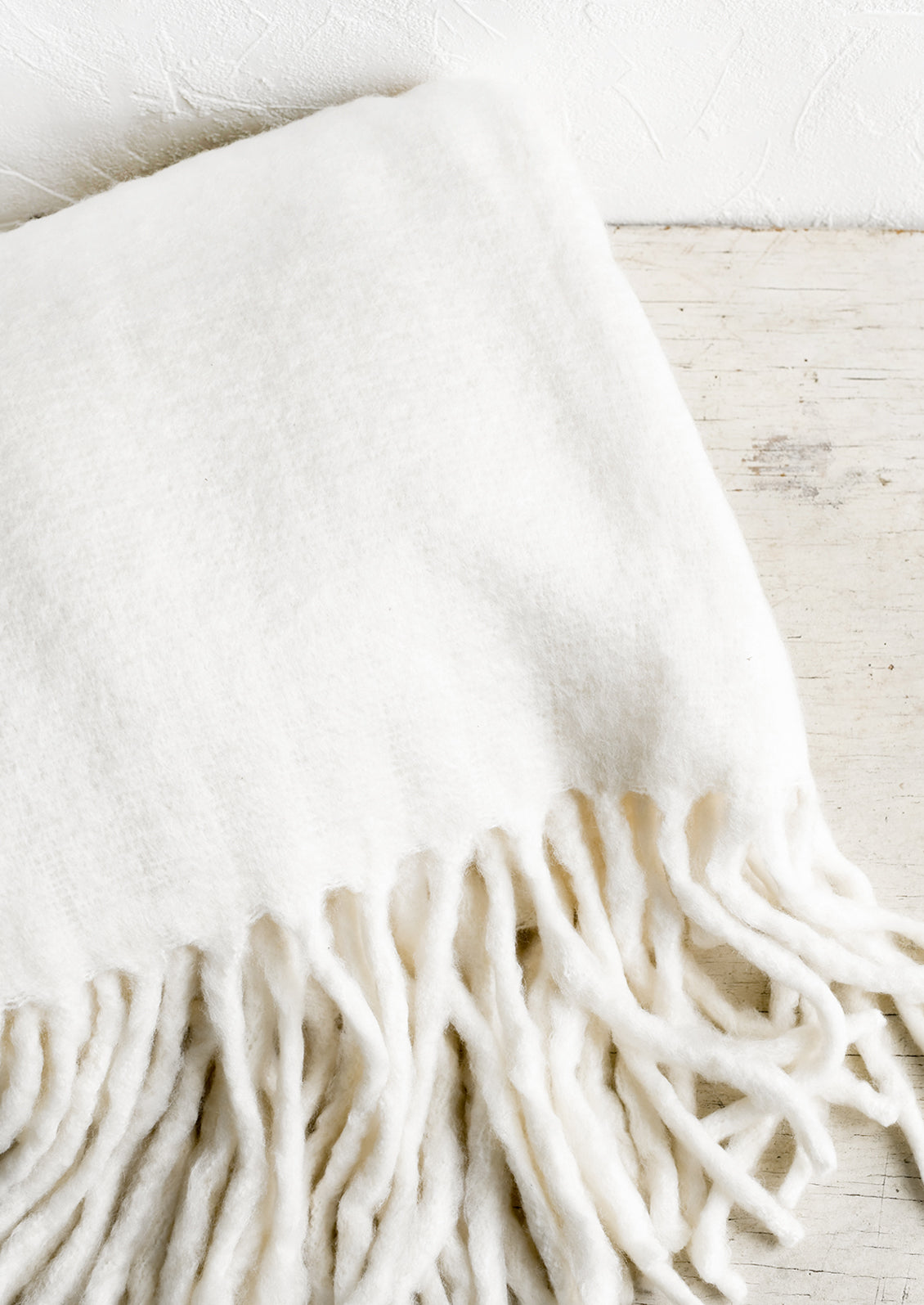 A fuzzy ivory blanket with fringe.