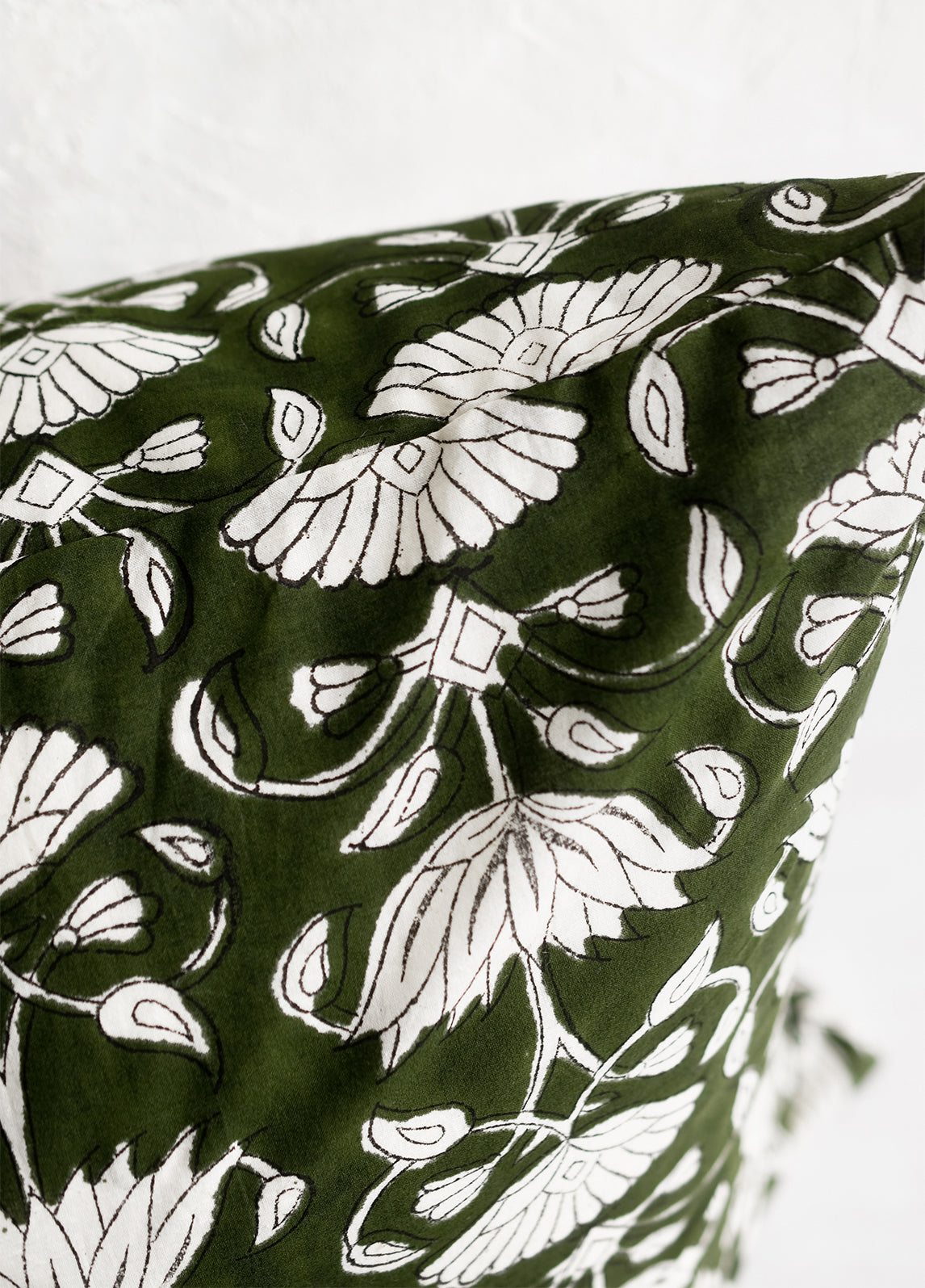 A block printed pillow in green and ivory floral motif.