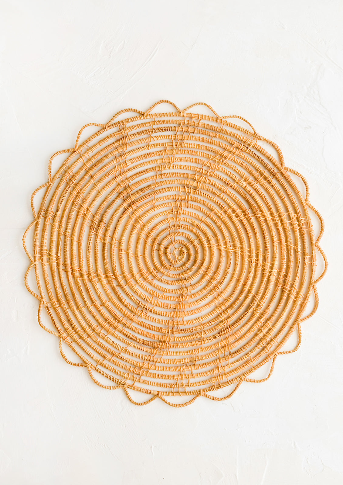 A round placemat with open weave scalloped edge.