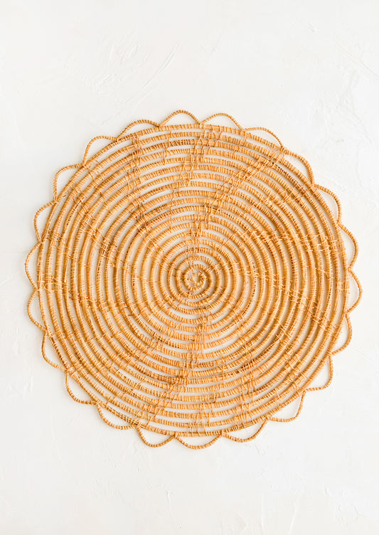 A round placemat with open weave scalloped edge.