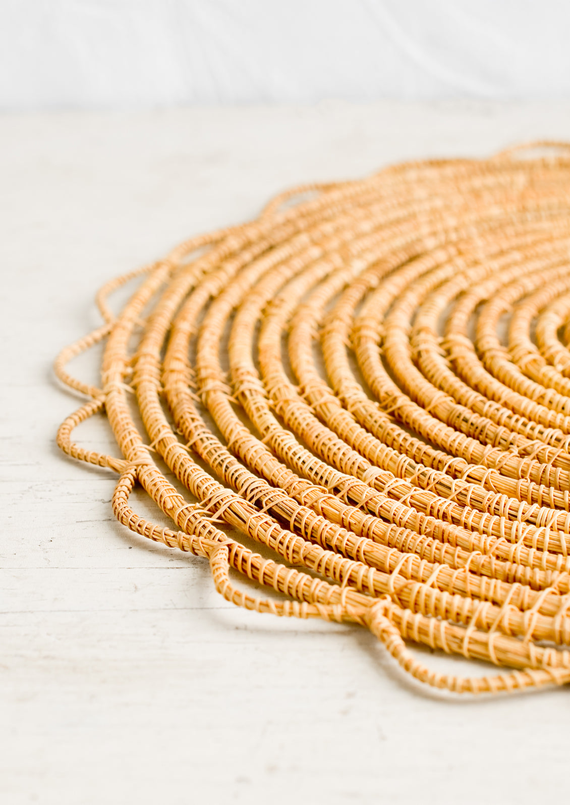 A round placemat with open weave scalloped edge.