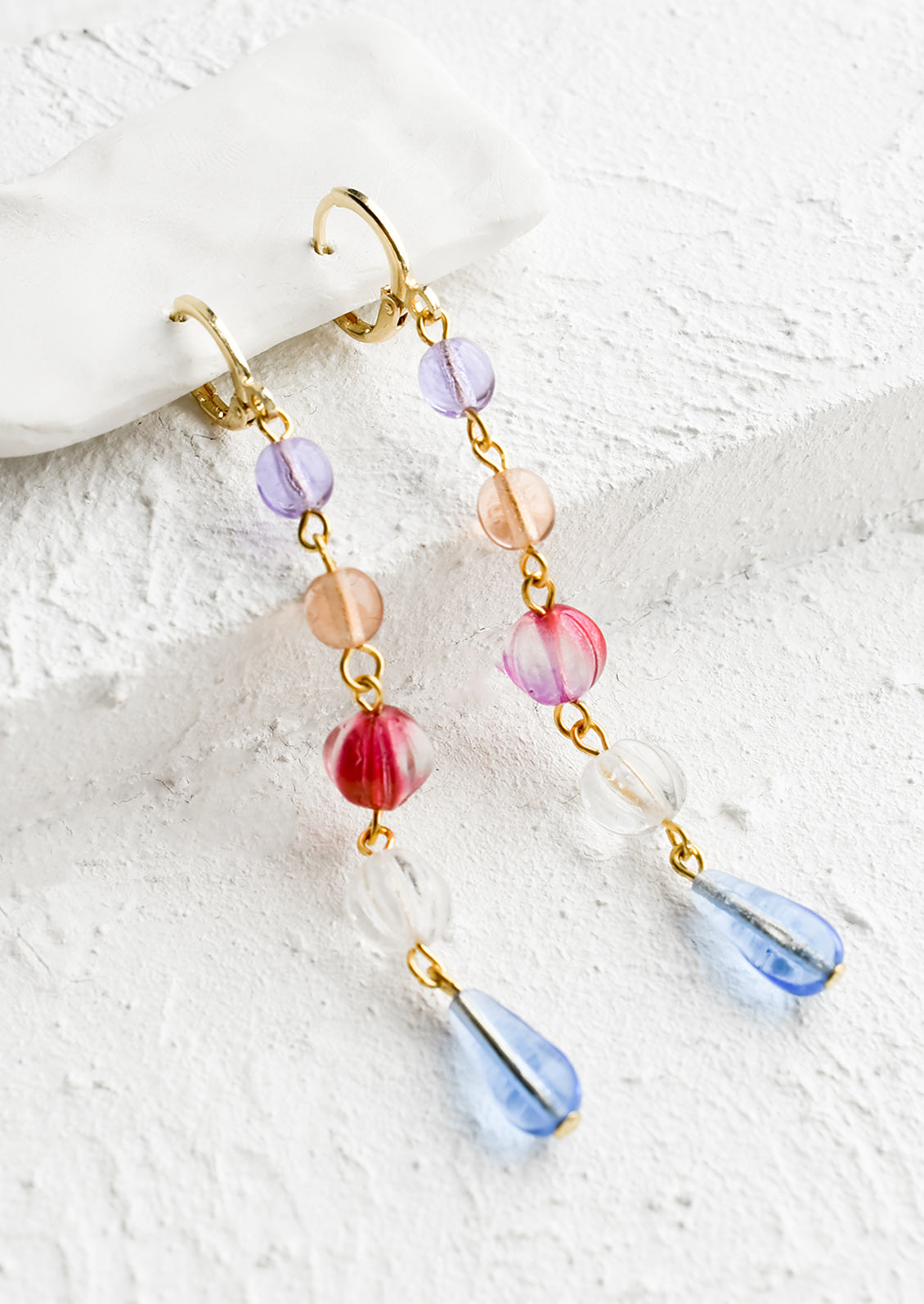 A pair of drop earrings with a beaded strand of colored glass beads with pearl detailing.