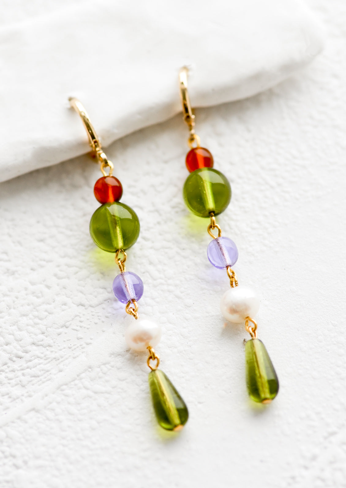 A pair of drop earrings with a beaded strand of colored glass beads with pearl detailing.