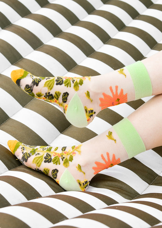 A person's ankles wearing sheer printed socks.