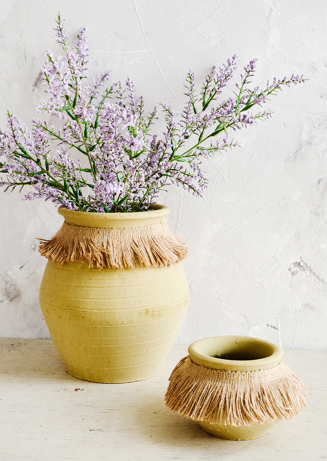 Clay pots with jute trim around neck, one displaying purple flowers