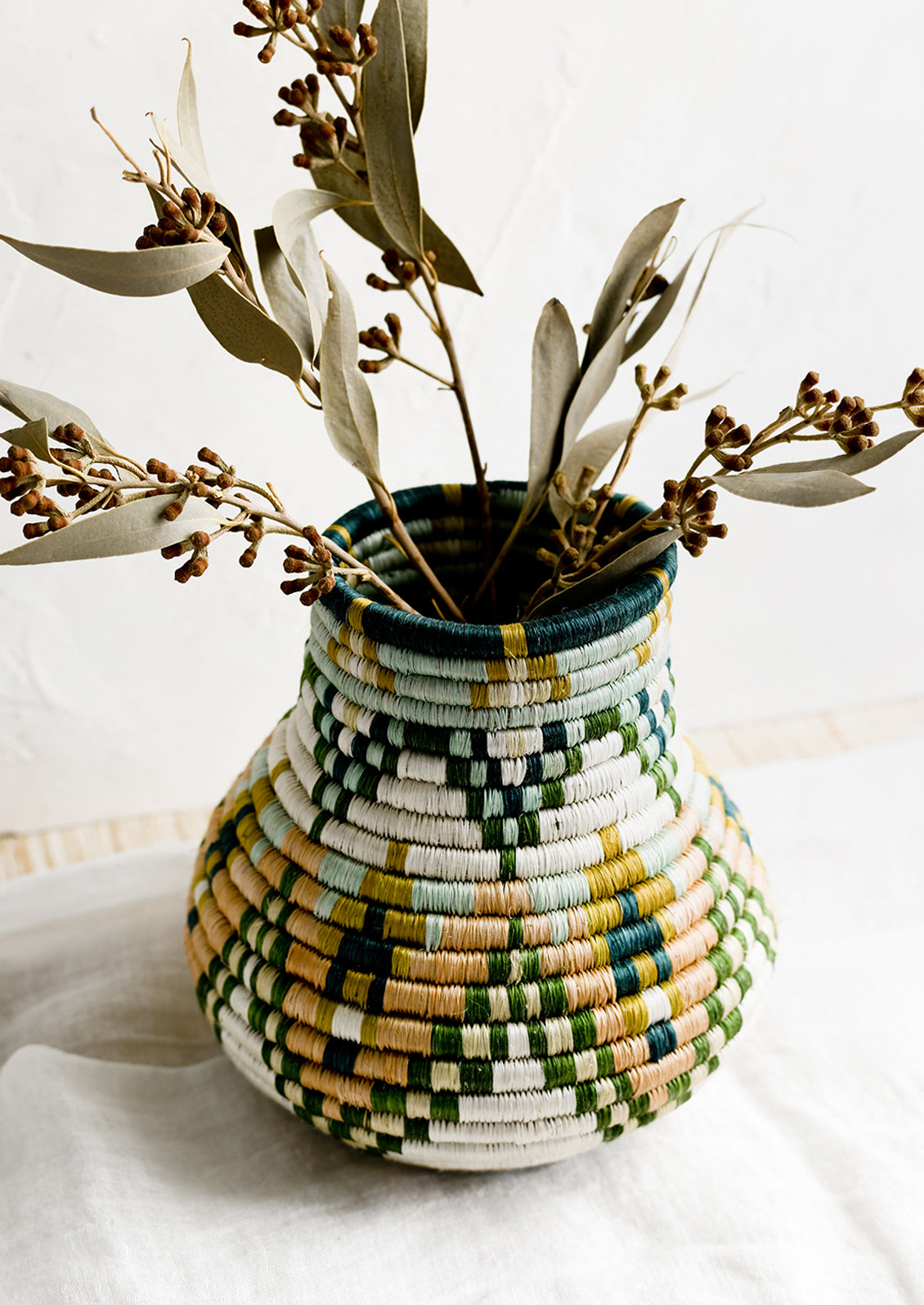 A woven sweetgrass vase holding dried eucalyptus.