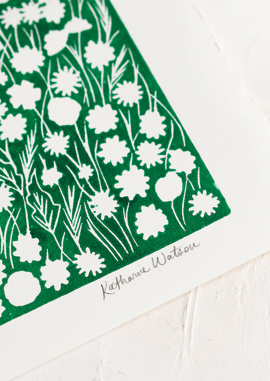 A block printed art print on deckled edge paper with green box with white flowers.