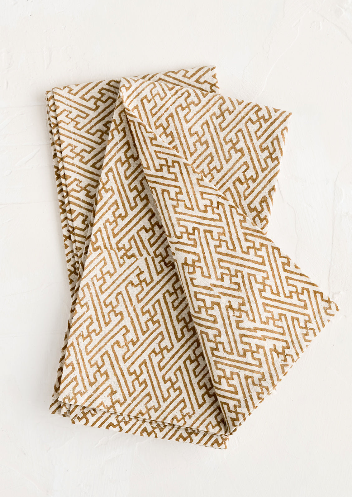 A pair of folded napkins with block printed labyrinth print on natural cotton.