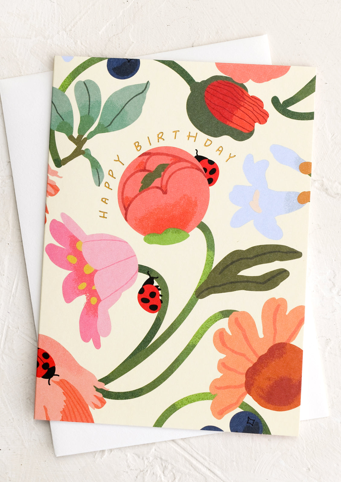 A floral print card with ladybugs reading "Happy Birthday".