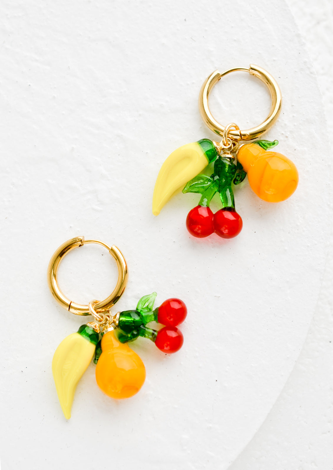 Gold hoop earrings with glass banana, cherry and orange fruit charms.