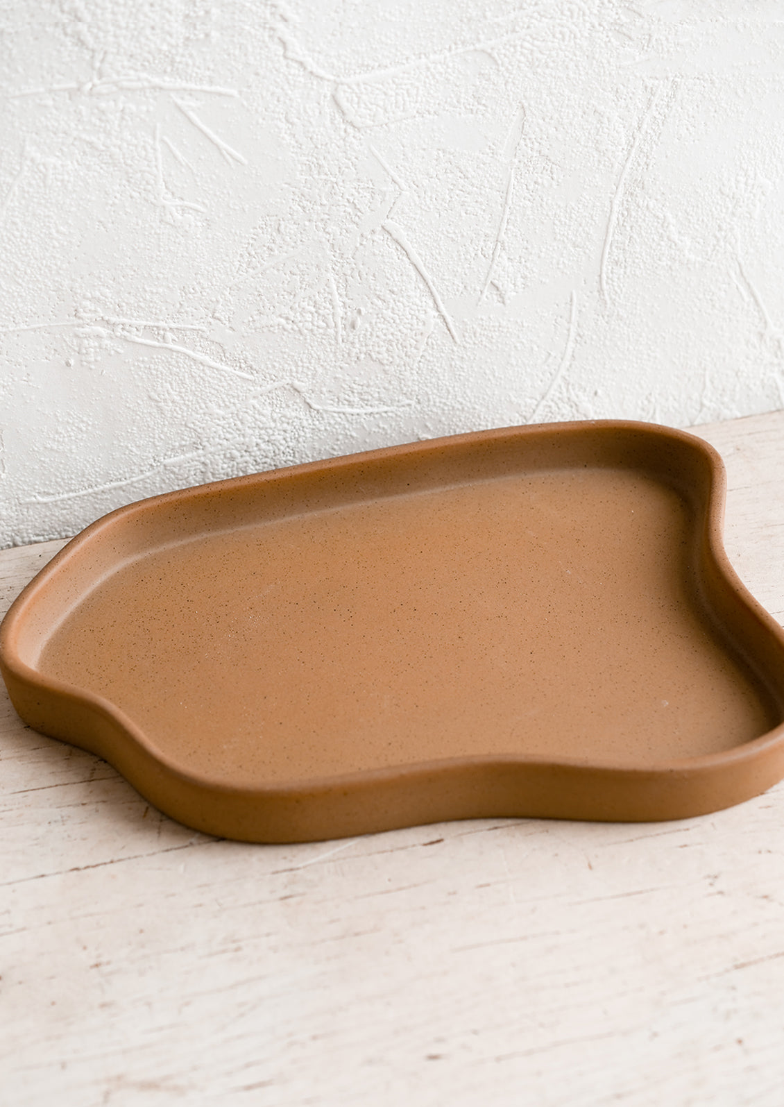 An asymmetrical large ceramic tray in matte brown.