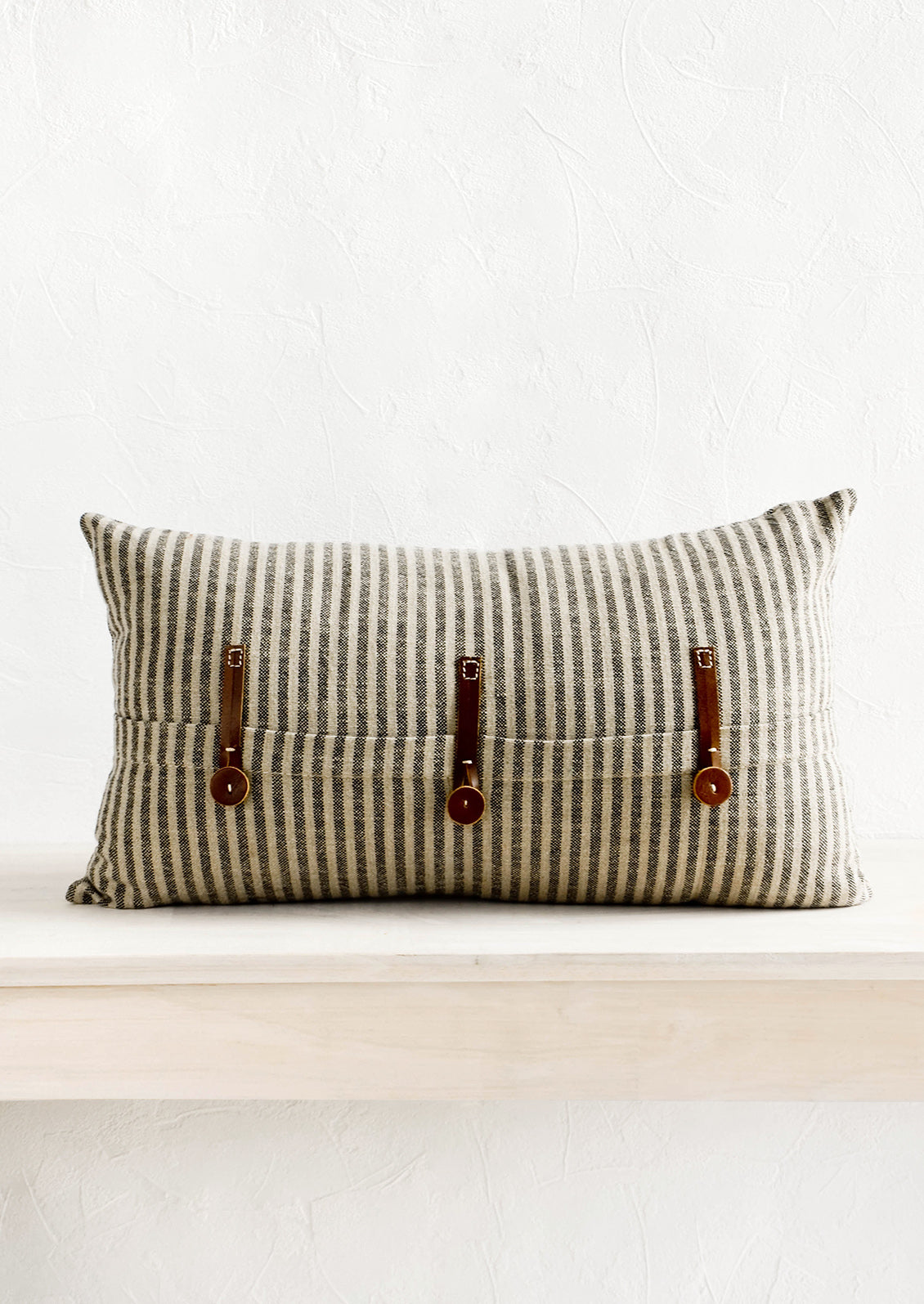 Striped cotton lumbar pillow in black and beige with decorative leather button detailing