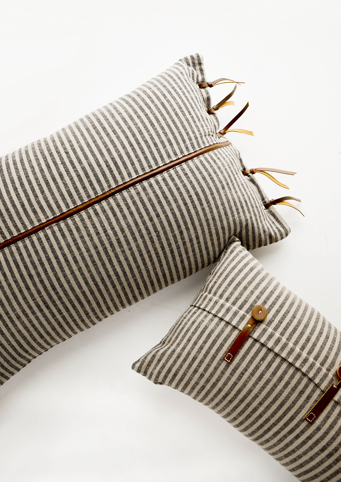 Lumbar throw pillows in tan and black striped fabric with brown leather details