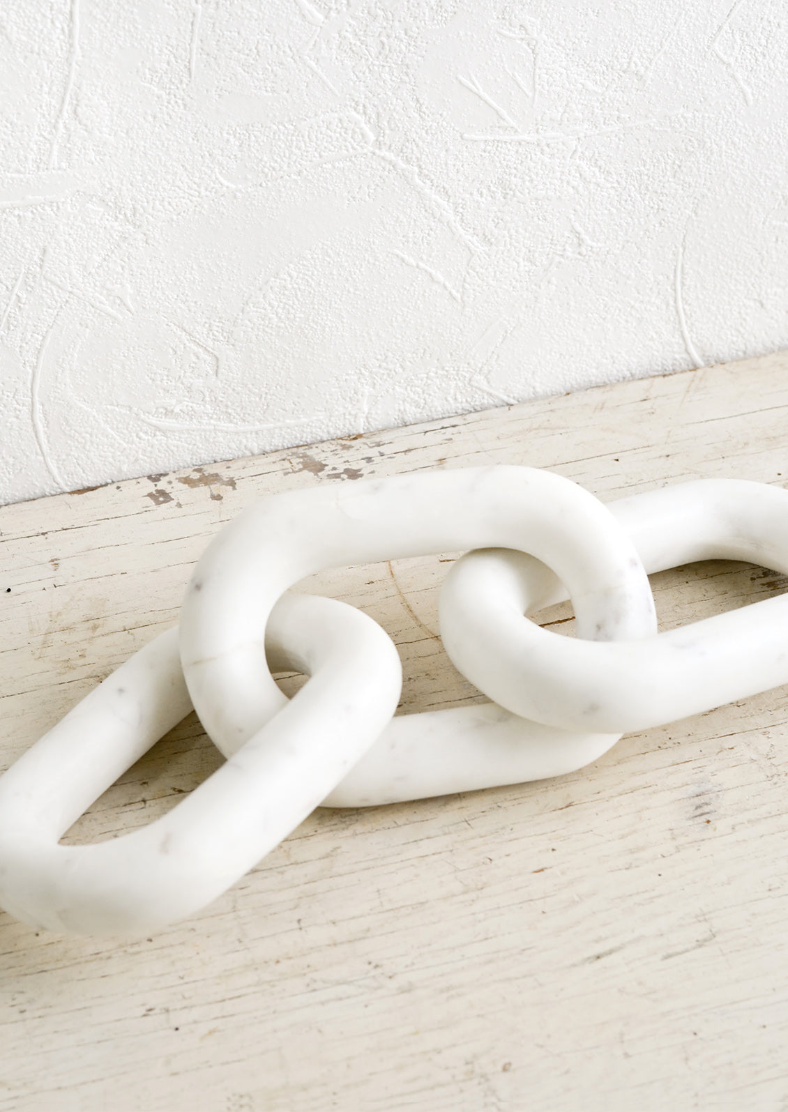 A decorative object made from solid white marble in the shape of three chainlinks.