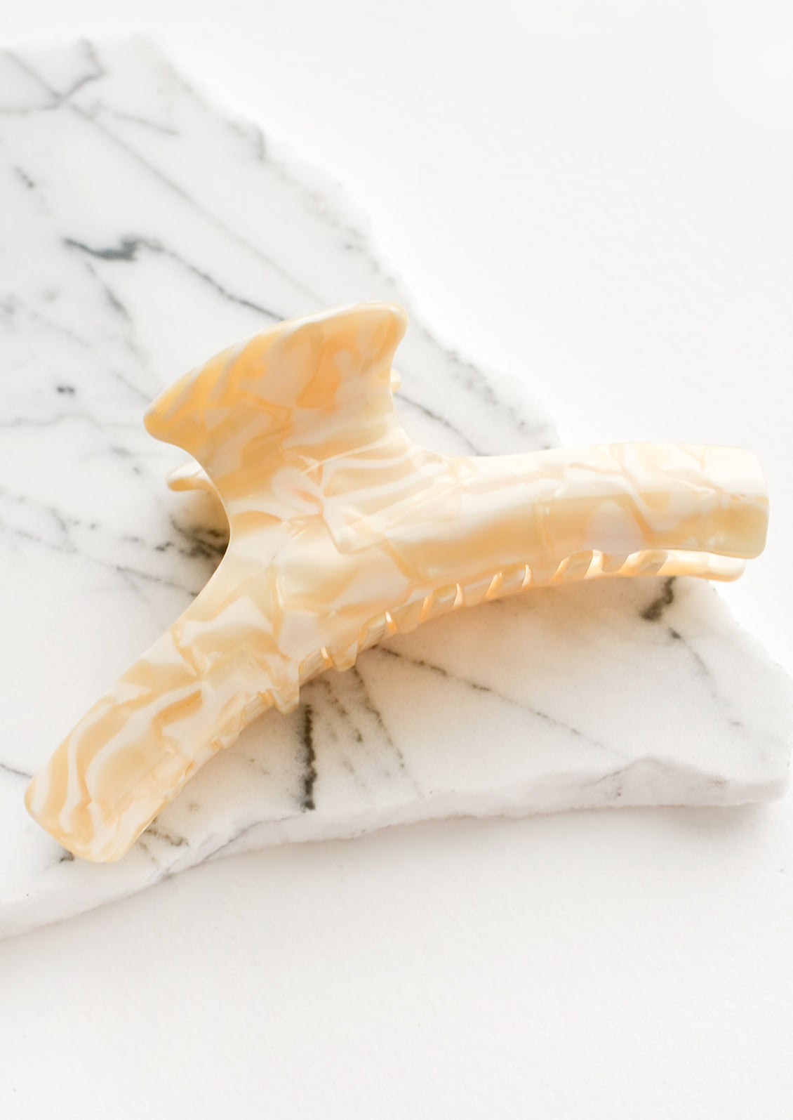 A hinged hair claw in marbled ivory and white acetate.