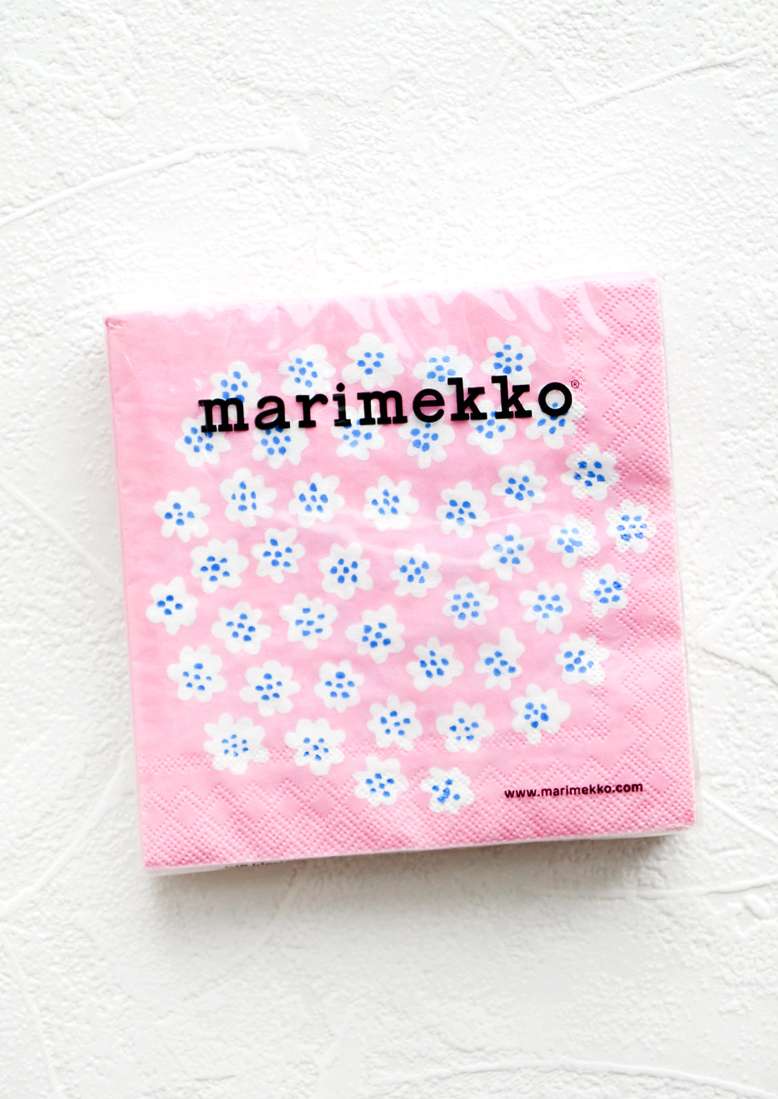 Packaged disposable paper napkins in square cocktail size with pink, blue and white floral print.