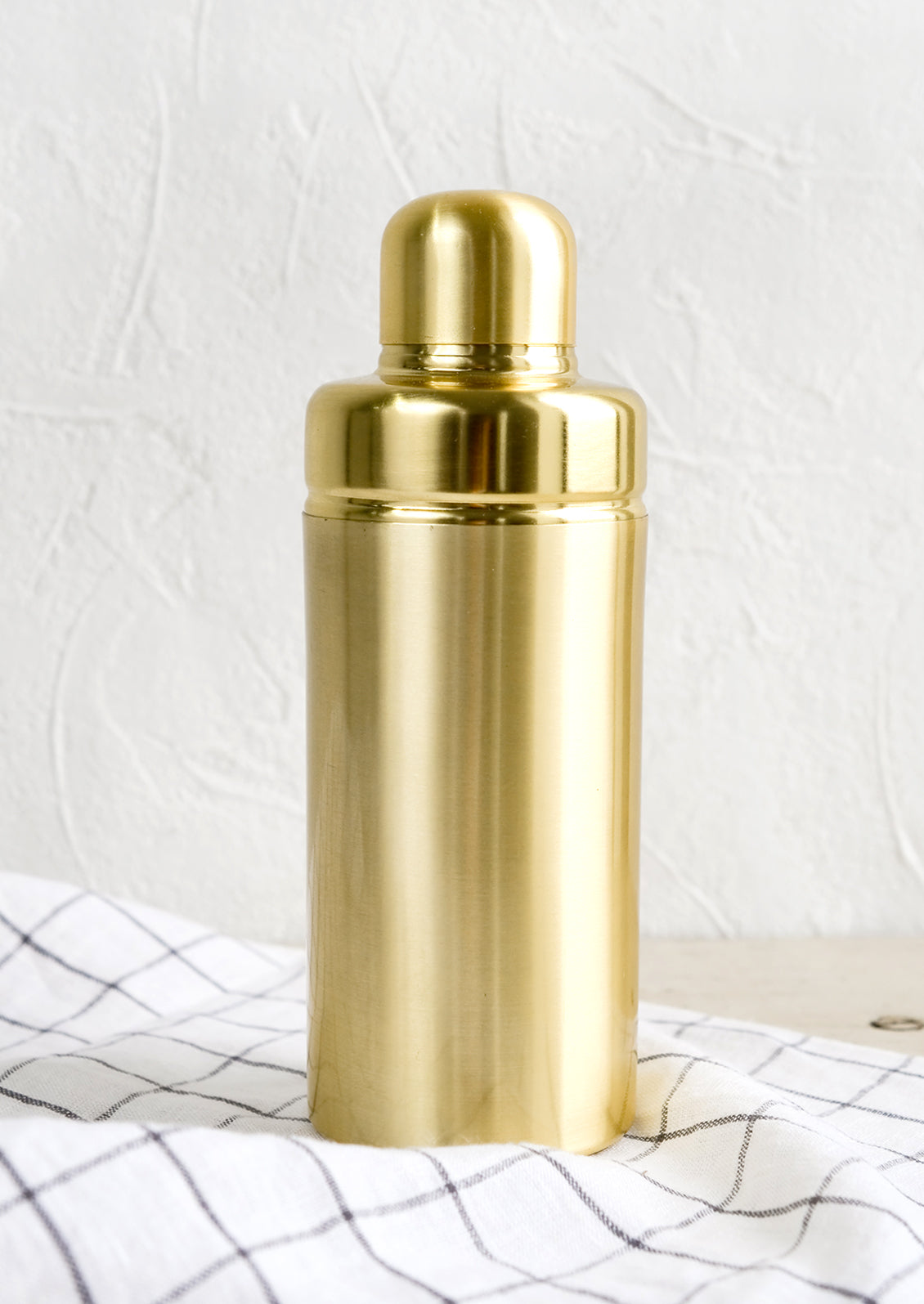 A cocktail shaker in satin gold metal.