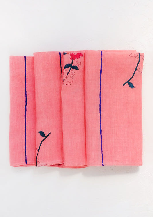 A folded pink linen napkin with block printed flowers and stripes.