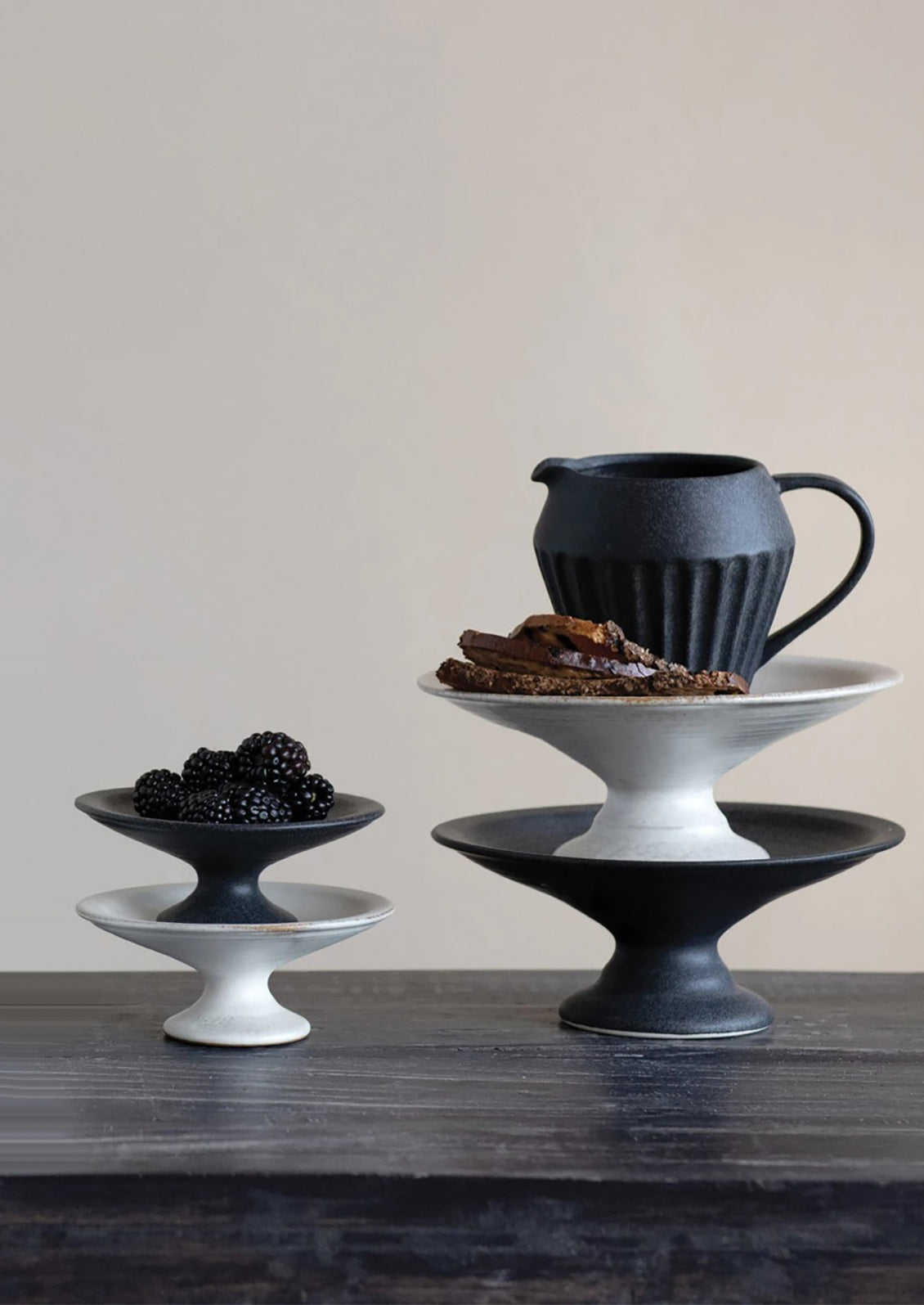 Ceramic pedestal risers in black and white styled with food.