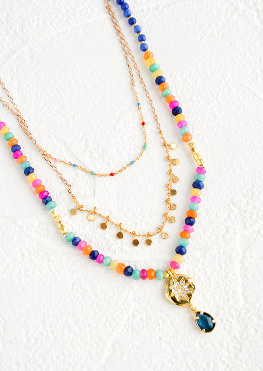 Triple strand layered necklace with beaded outer strand and gold inner strands.