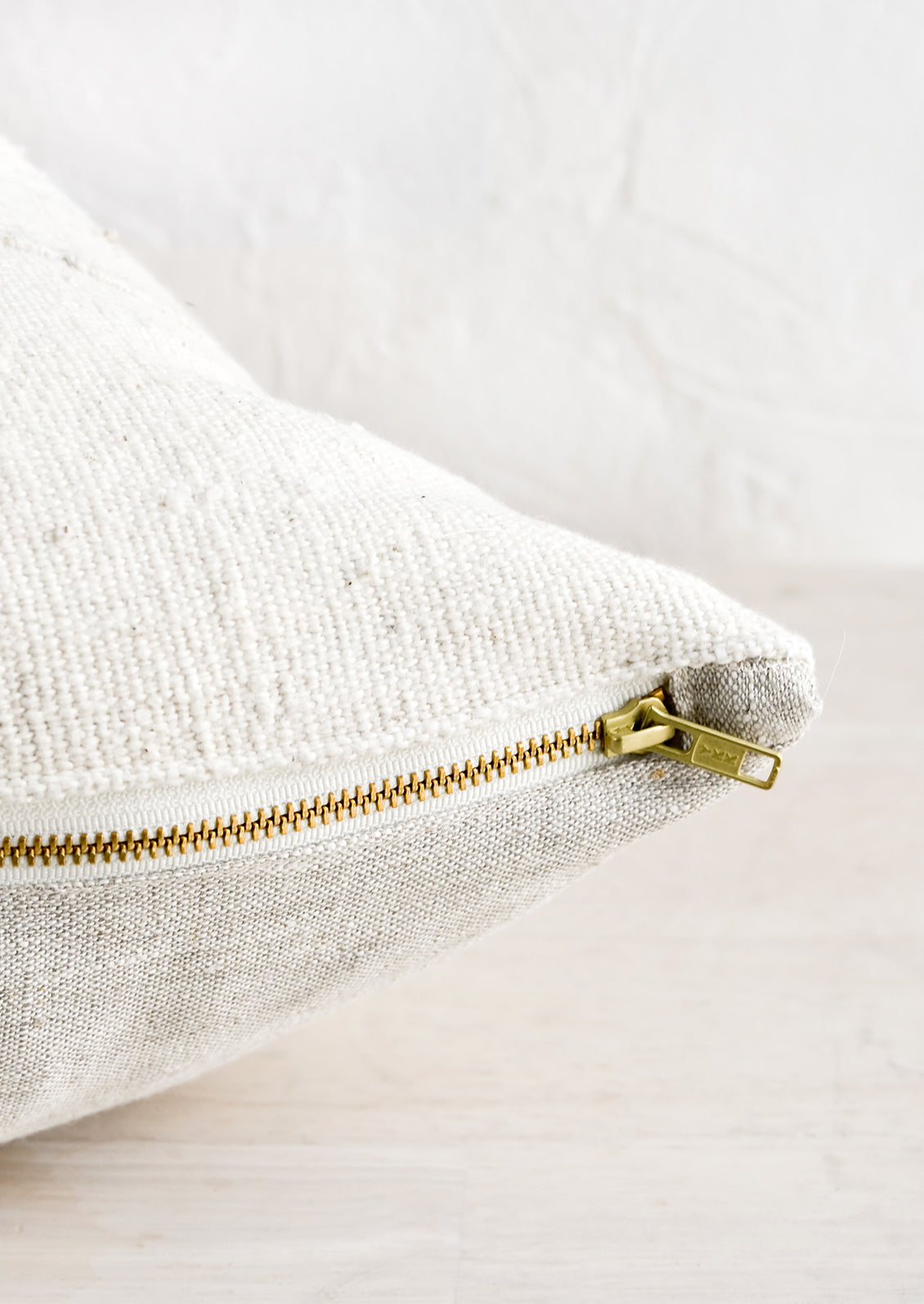 An exposed brass zipper on the bottom of a throw pillow.