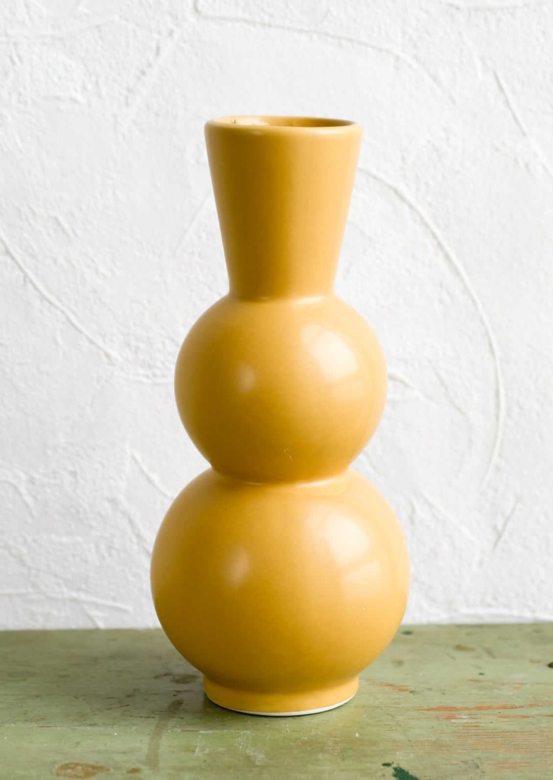 A yellow ceramic vase with curvy, tall silhouette.