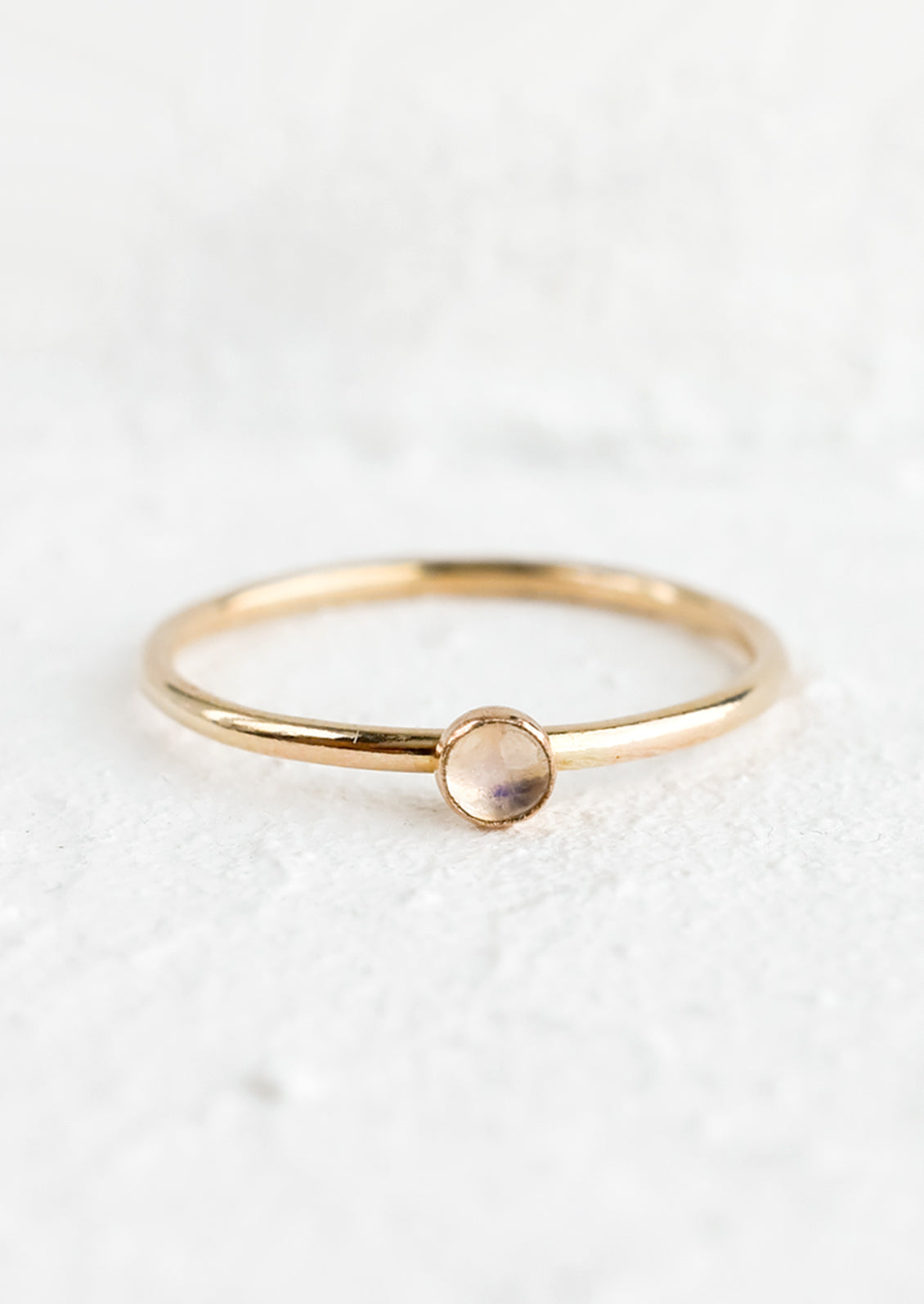 A thin gold ring with round bezeled moonstone.