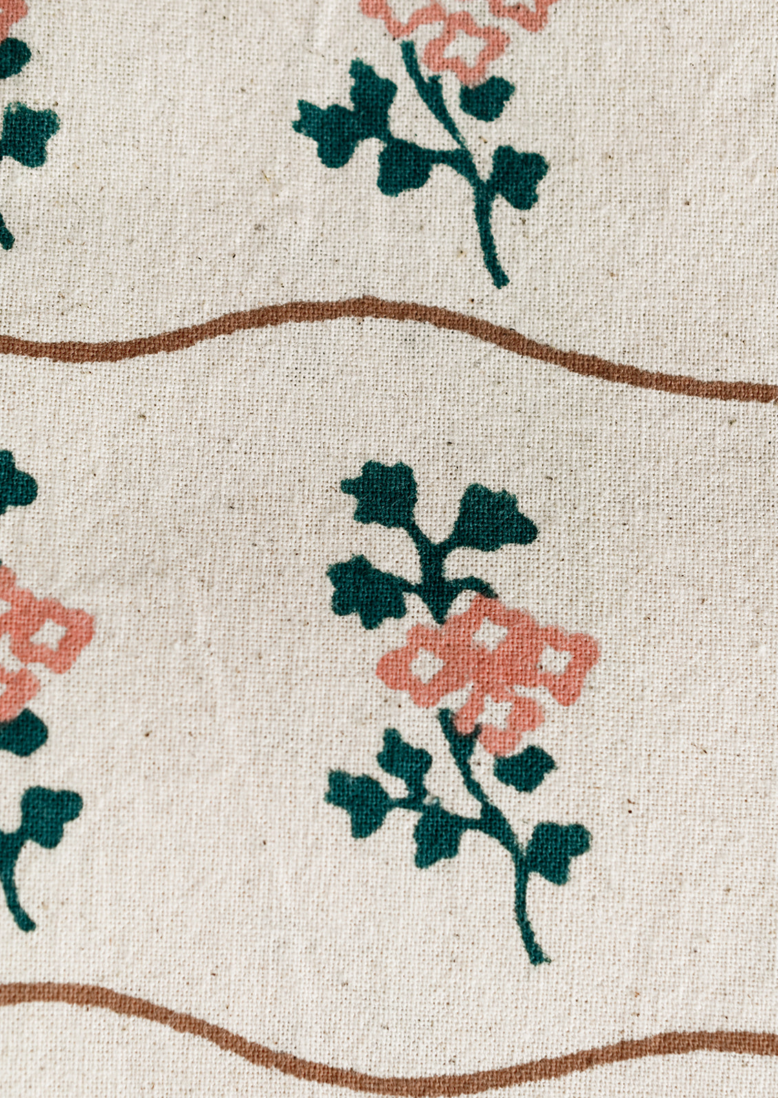 A natural cotton napkin with wavy brown line and green/peach flower print.