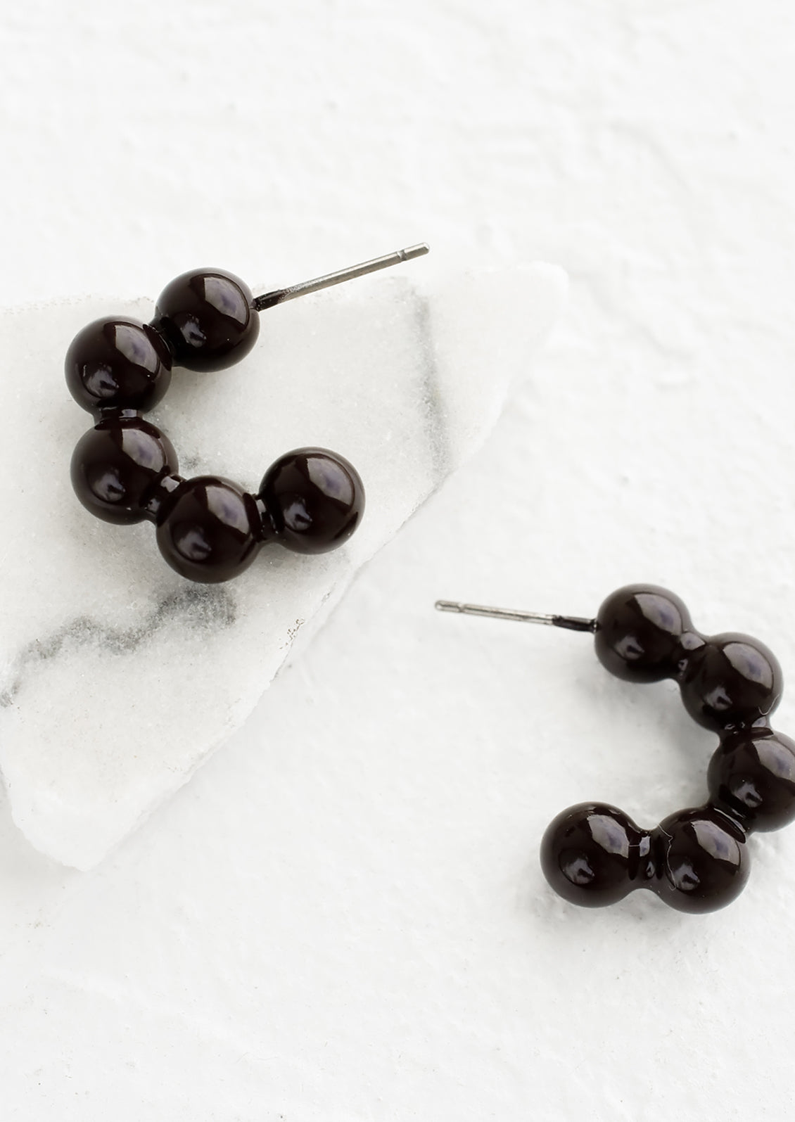 Glossy ball hoop earrings in very dark brown color.