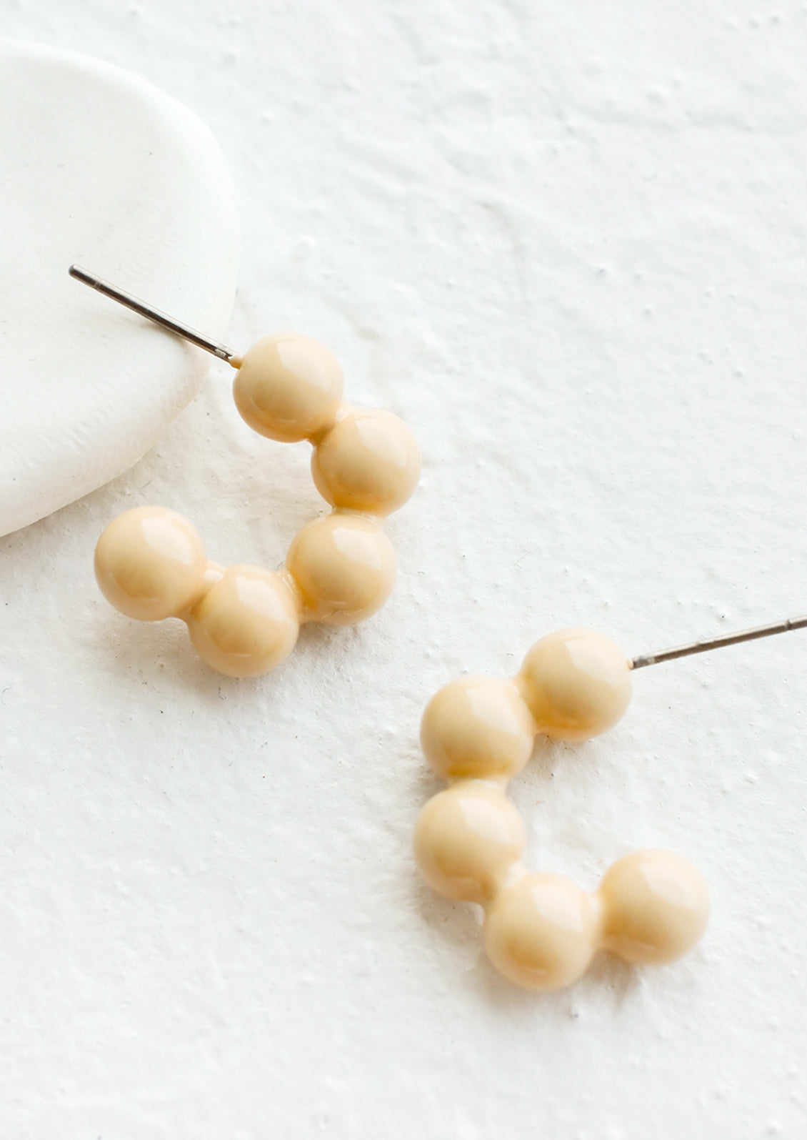 Glossy ball hoop earrings in cream color.