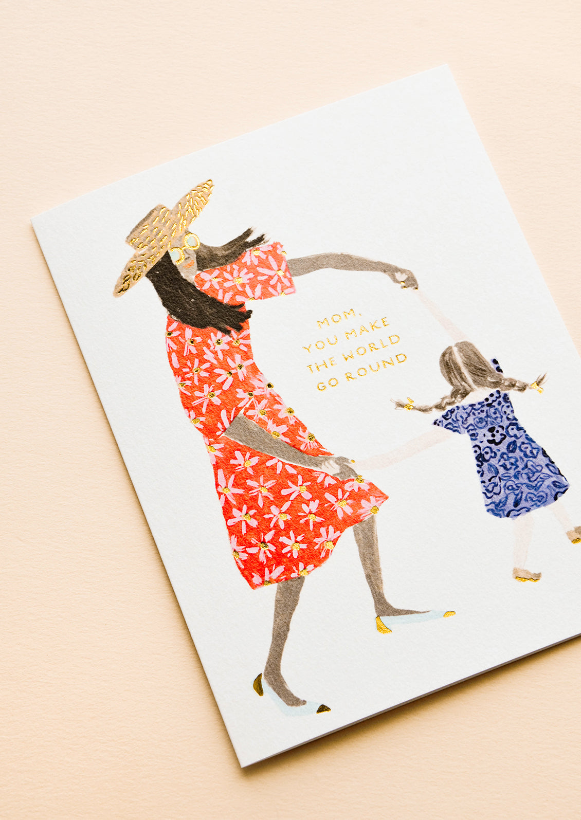 Greeting card picturing illustration of mother and child, text reading "Mom, You Make The World Go Round"