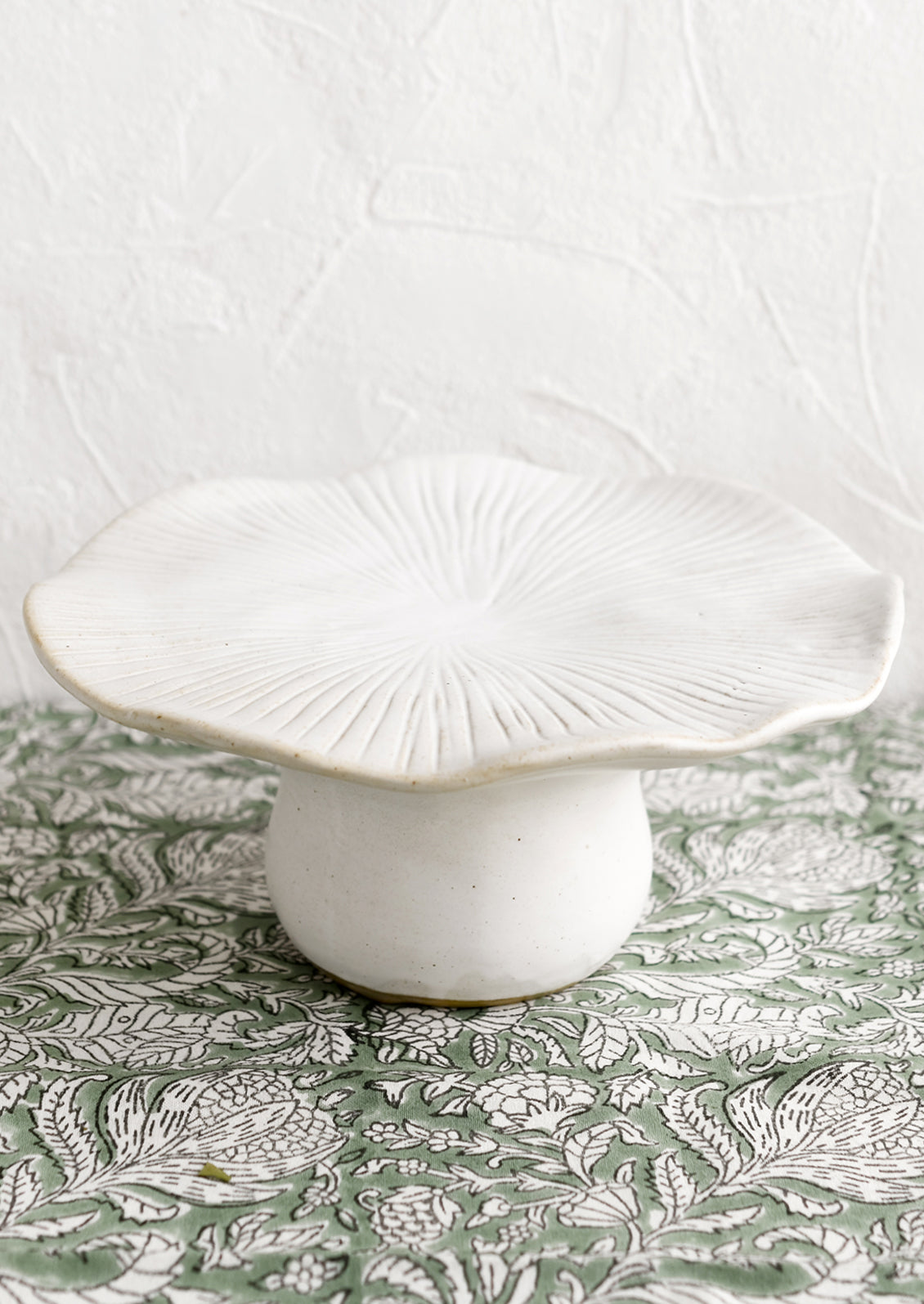 A white ceramic pedestal in the shape of a mushroom with flat top.