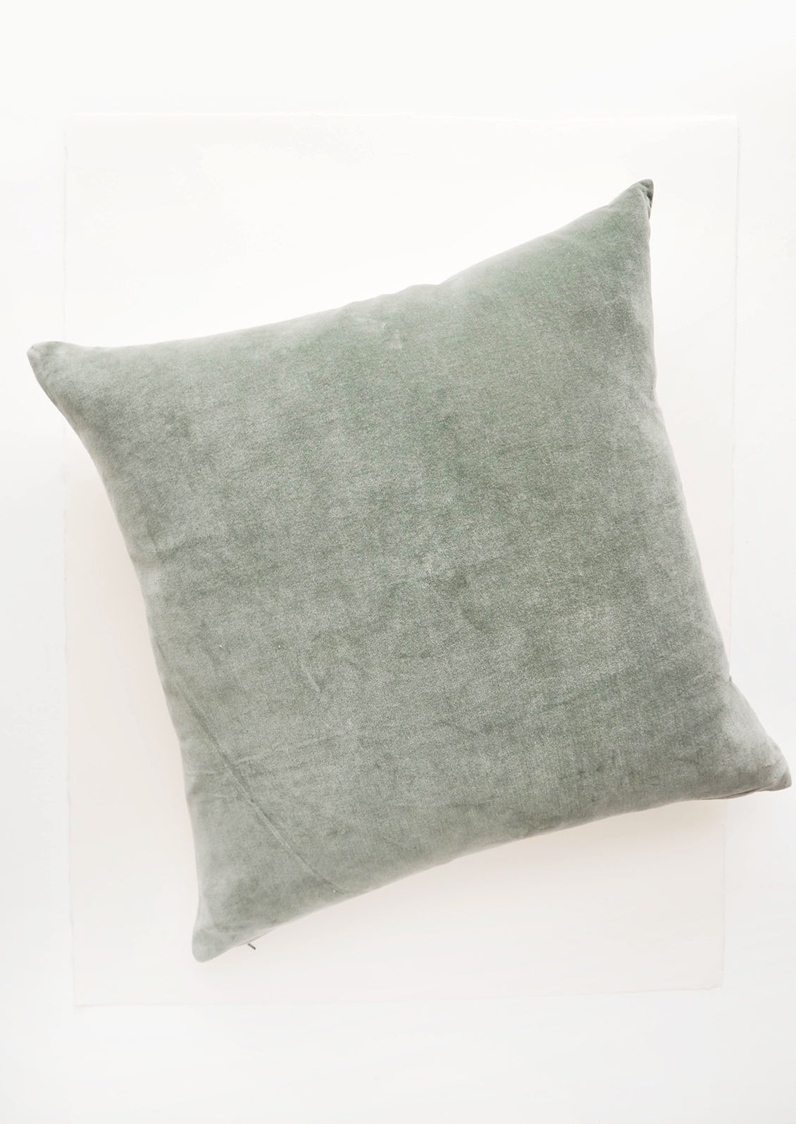 A square velvet throw pillow in celadon.