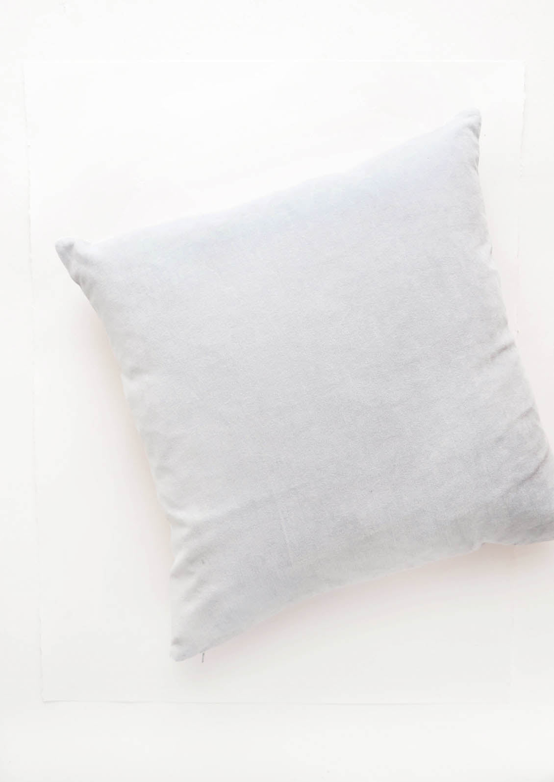 A square velvet throw pillow in light blue.