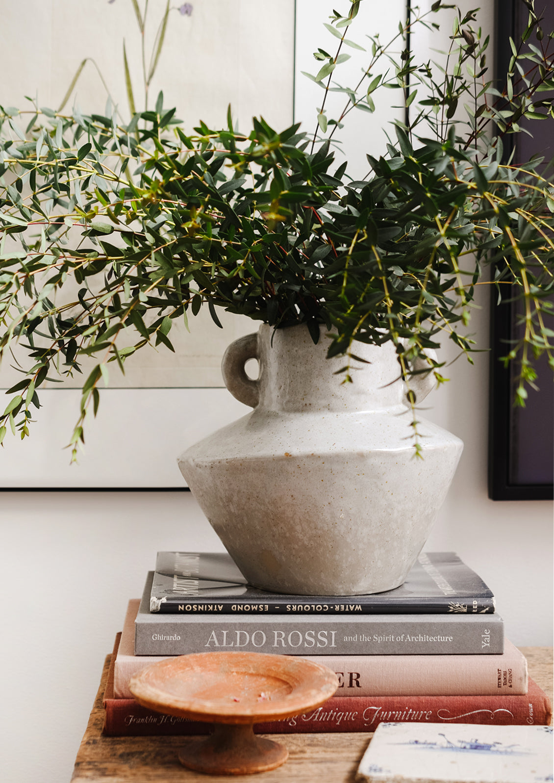 A grey vase with eucalyptus.