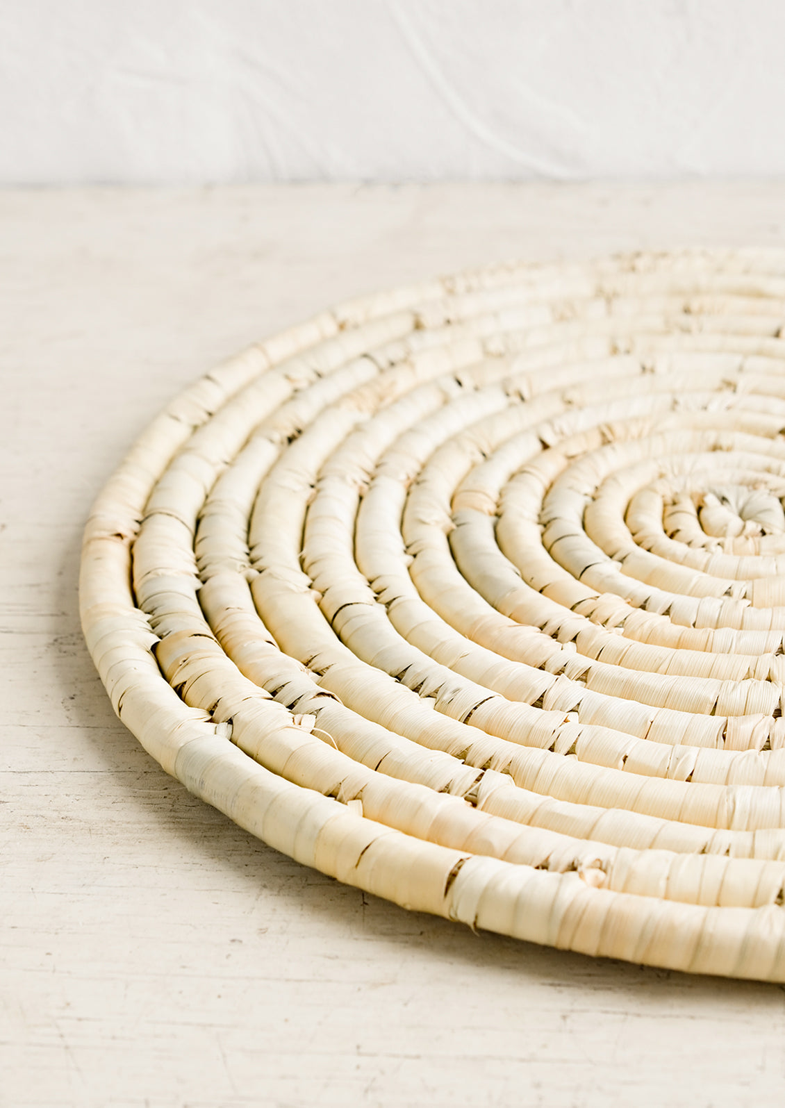 A round placemat made from natural dried straw.