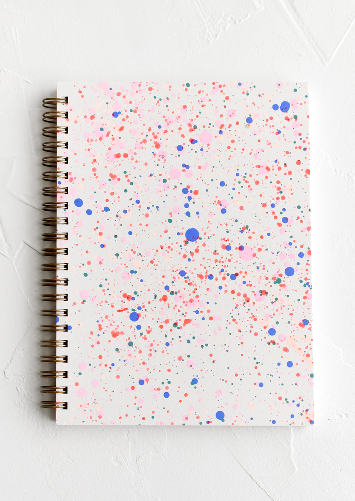 Spiral bound notepad with neon paint splatter cover.